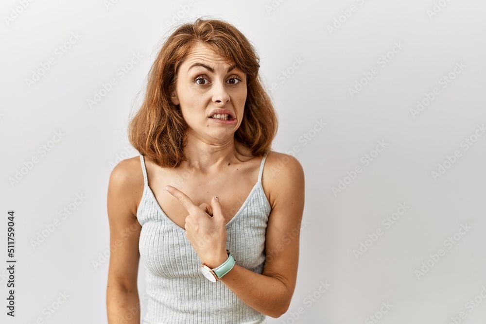 Beautiful caucasian woman standing over isolated background pointing aside worried and nervous with forefinger, concerned and surprised expression Beautiful caucasian woman standing over isolated background pointing aside worried and nervous with forefinger, concerned and surprised expression