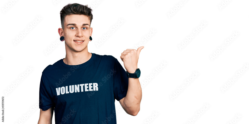 Young caucasian boy with ears dilation wearing volunteer t shirt pointing to the back behind with hand and thumbs up, smiling confident Young caucasian boy with ears dilation wearing volunteer t shirt pointing to the back behind with hand and thumbs up, smiling confident
