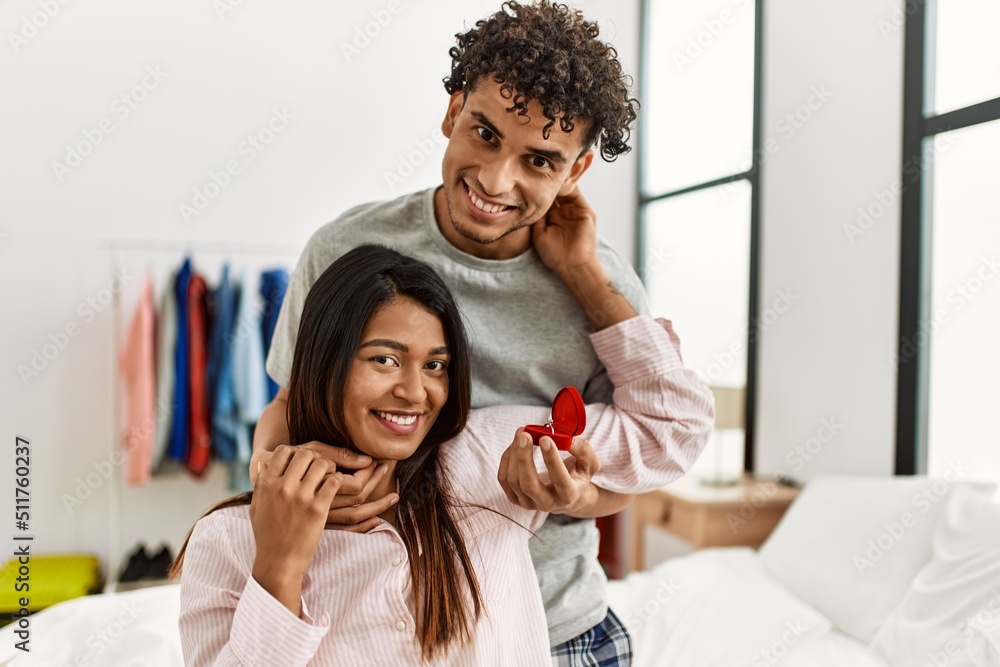 Obraz premium Young latin couple on marriage proposal holding engagement ring at the bedroom.