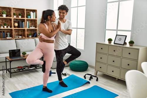 Young latin couple smiling happy training yoga pose at home.