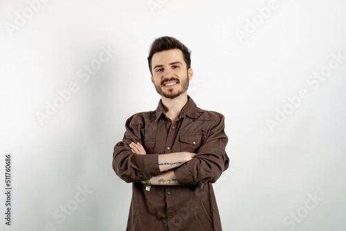 Cheerful caucasian man wearing brown shirt posing isolated over white background smiling with crossed arms looking at the camera. Positive person.