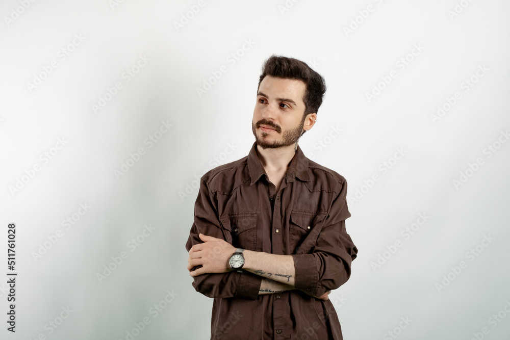Obraz premium Handsome caucasian man wearing casual clothes posing isolated over white background keeping arms crossed and looking away with smile.