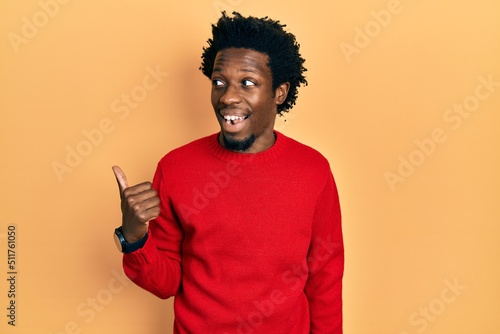 Young african american man wearing casual clothes pointing thumb up to the side smiling happy with open mouth