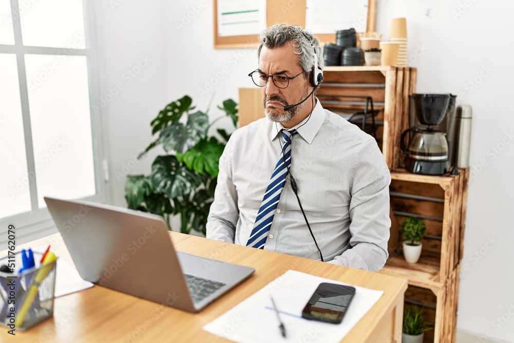 Middle age hispanic business man working at the office wearing operator headset depressed and worry for distress, crying angry and afraid. sad expression. Middle age hispanic business man working at the office wearing operator headset depressed and worry for distress, crying angry and afraid. sad expression.