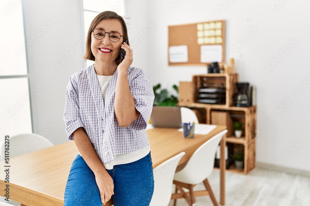 Middle age hispanic woman businesswoman using smartphone at business office Middle age hispanic woman businesswoman using smartphone at business office