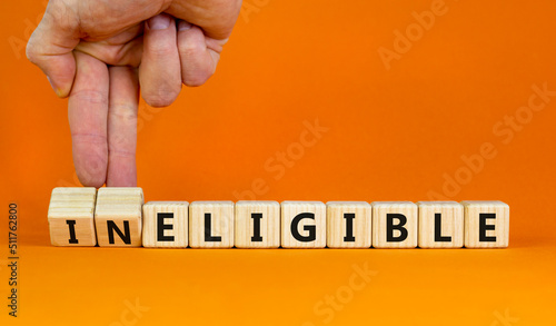 Eligible or ineligible symbol. Businessman turns wooden cubes and changes words Ineligible to Eligible. Beautiful orange table orange background. Business eligible or ineligible concept. Copy space. photo