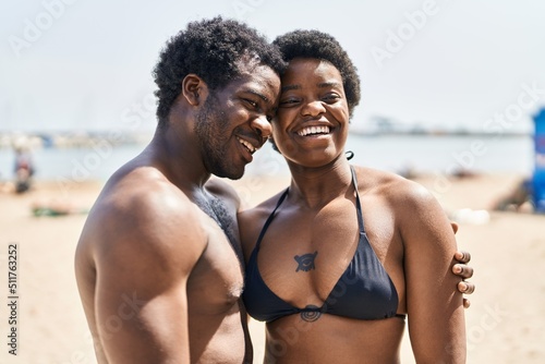 African american man and woman couple wearing swimsuit hugging each other at seaside