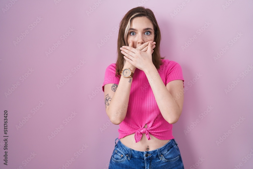 Blonde caucasian woman standing over pink background shocked covering mouth with hands for mistake. secret concept. Blonde caucasian woman standing over pink background shocked covering mouth with hands for mistake. secret concept.