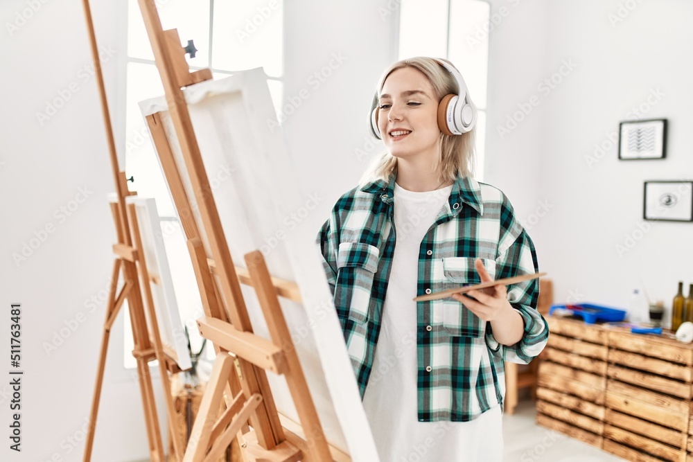 Young artist student girl smiling happy painting and listening music at art studio. Young artist student girl smiling happy painting and listening music at art studio.