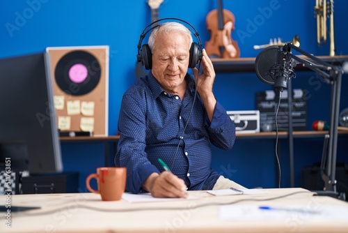 Senior grey-haired man musician composing song at music studio