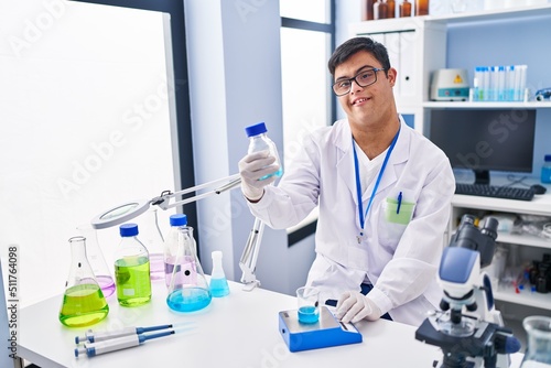 Down syndrome man wearing scientist uniform measuring liquid at laboratory