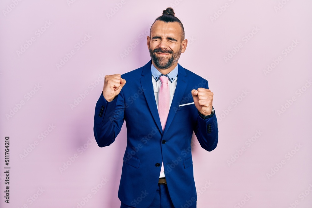 Young hispanic man wearing business suit and tie excited for success with arms raised and eyes closed celebrating victory smiling. winner concept. Young hispanic man wearing business suit and tie excited for success with arms raised and eyes closed celebrating victory smiling. winner concept.