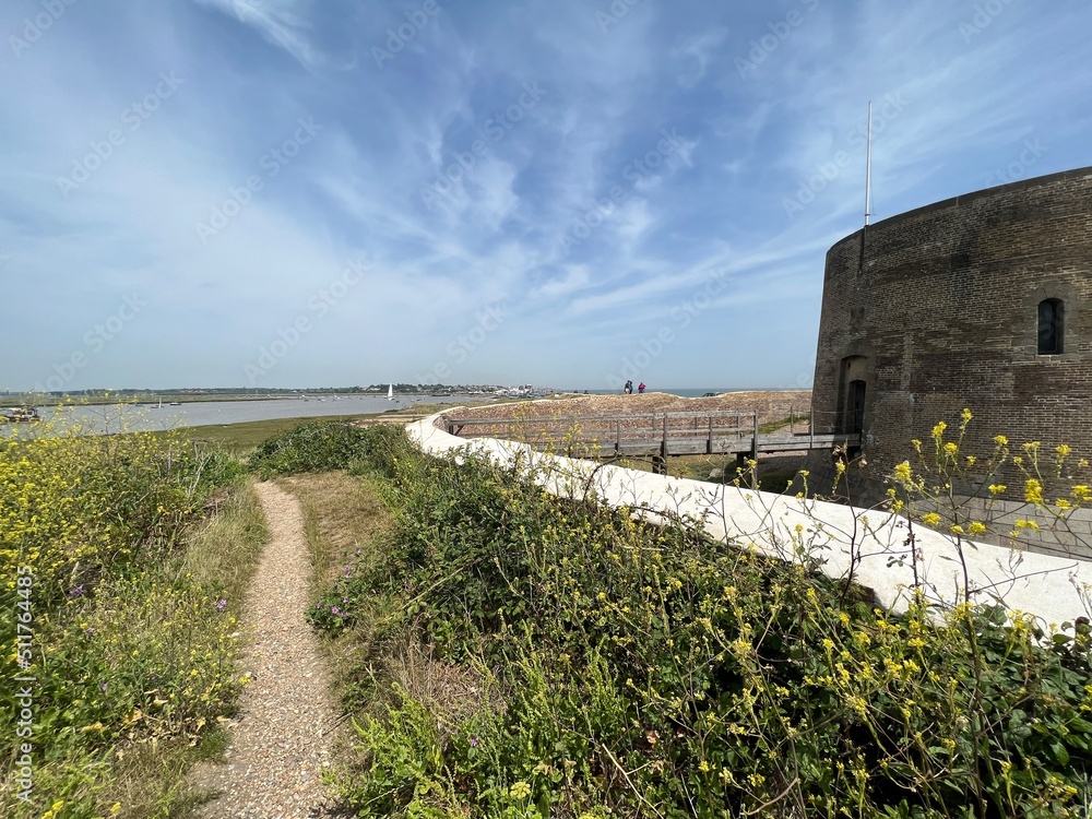  Landscape with Martello tower historic stone forts built as 19th century sea defences on East Anglia coastline Aldeburgh beach Suffolk uk with wooden bridge over moat in Summer blue skies 
