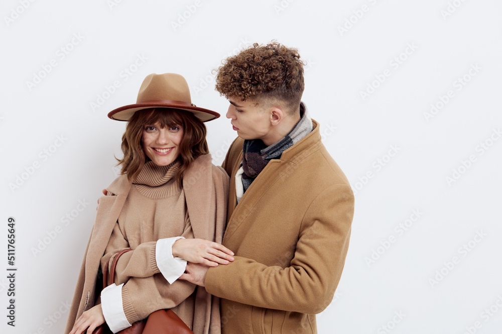 a happy couple a man and a woman are standing in stylish autumn clothes on a white background close to each other and a man looks tenderly at a woman a happy couple a man and a woman are standing in stylish autumn clothes on a white background close to each other and a man looks tenderly at a woman