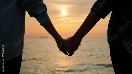 Couple holding hands together. Loving couple holding hands relaxing and walking down the beach at sunrise.