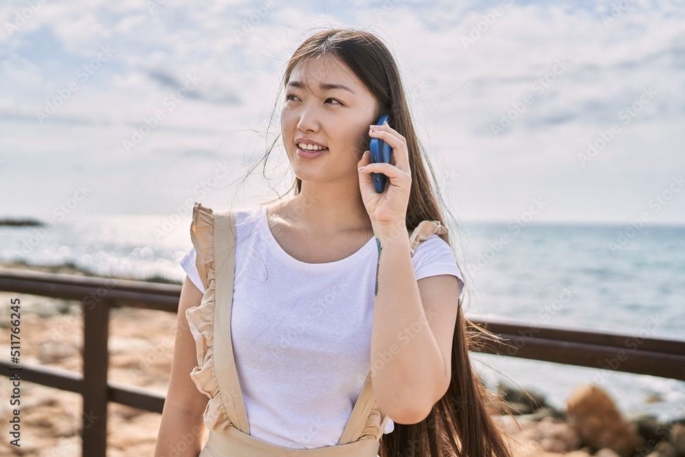 Young chinese girl smiling happy talking on the smartphone at the beach. Young chinese girl smiling happy talking on the smartphone at the beach.