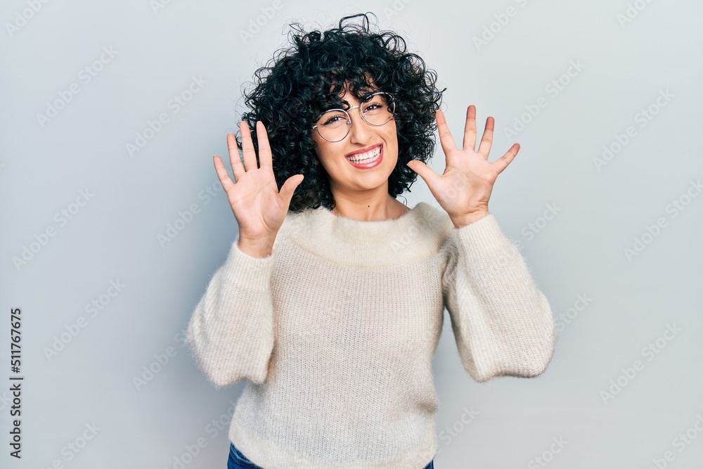 Young middle east woman wearing casual white tshirt showing and pointing up with fingers number ten while smiling confident and happy. Young middle east woman wearing casual white tshirt showing and pointing up with fingers number ten while smiling confident and happy.
