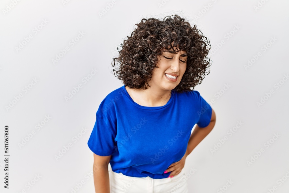 Young middle eastern woman standing over isolated background with hand on stomach because indigestion, painful illness feeling unwell. ache concept. Young middle eastern woman standing over isolated background with hand on stomach because indigestion, painful illness feeling unwell. ache concept.
