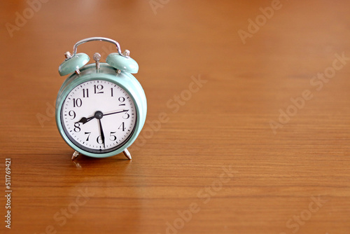 A turquoise green alarm clock on a wooden table