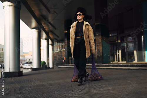 A girl in a sweatshirt poses in a modern city. Fashion photo shoot with potatoes.