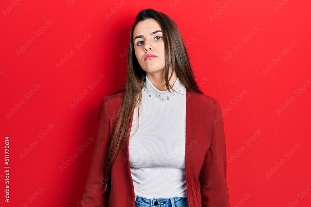 Young brunette teenager wearing business jacket relaxed with serious expression on face. simple and natural looking at the camera. Young brunette teenager wearing business jacket relaxed with serious expression on face. simple and natural looking at the camera.