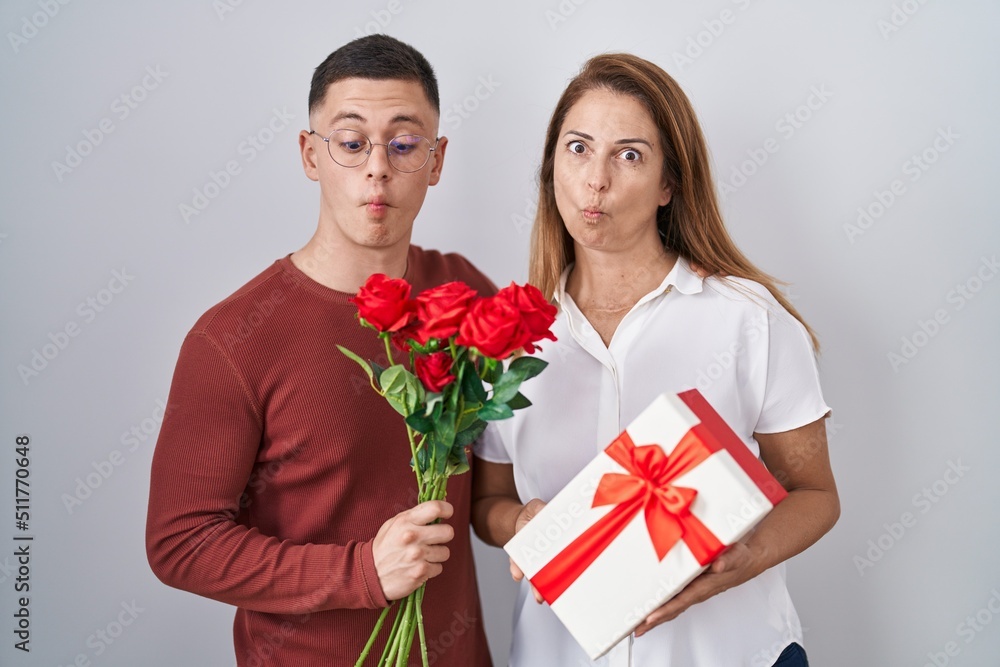 Mother and son holding mothers day gift making fish face with mouth and squinting eyes, crazy and comical. Mother and son holding mothers day gift making fish face with mouth and squinting eyes, crazy and comical.