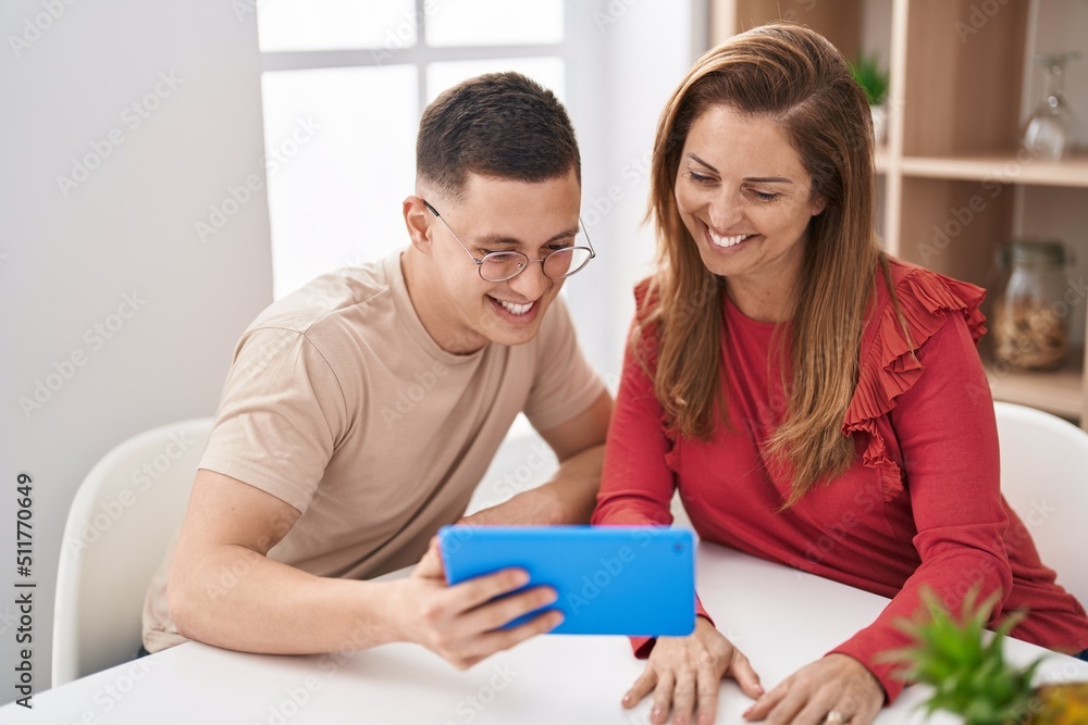 Man and woman mother and son using touchpad sitting on table at home Man and woman mother and son using touchpad sitting on table at home