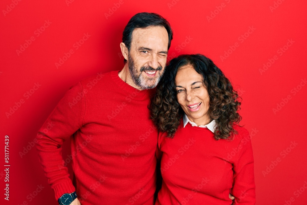 Middle age couple of hispanic woman and man hugging and standing together winking looking at the camera with sexy expression, cheerful and happy face. Middle age couple of hispanic woman and man hugging and standing together winking looking at the camera with sexy expression, cheerful and happy face.