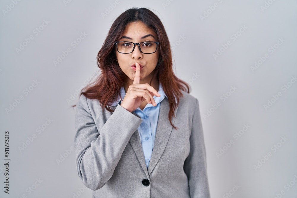 Hispanic young business woman wearing glasses asking to be quiet with finger on lips. silence and secret concept. Hispanic young business woman wearing glasses asking to be quiet with finger on lips. silence and secret concept.