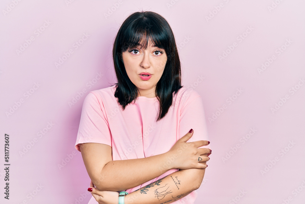 Obraz premium Young hispanic woman wearing casual clothes shaking and freezing for winter cold with sad and shock expression on face