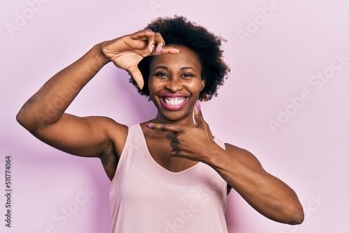 Young african american woman wearing casual sleeveless t shirt smiling making frame with hands and fingers with happy face. creativity and photography concept.