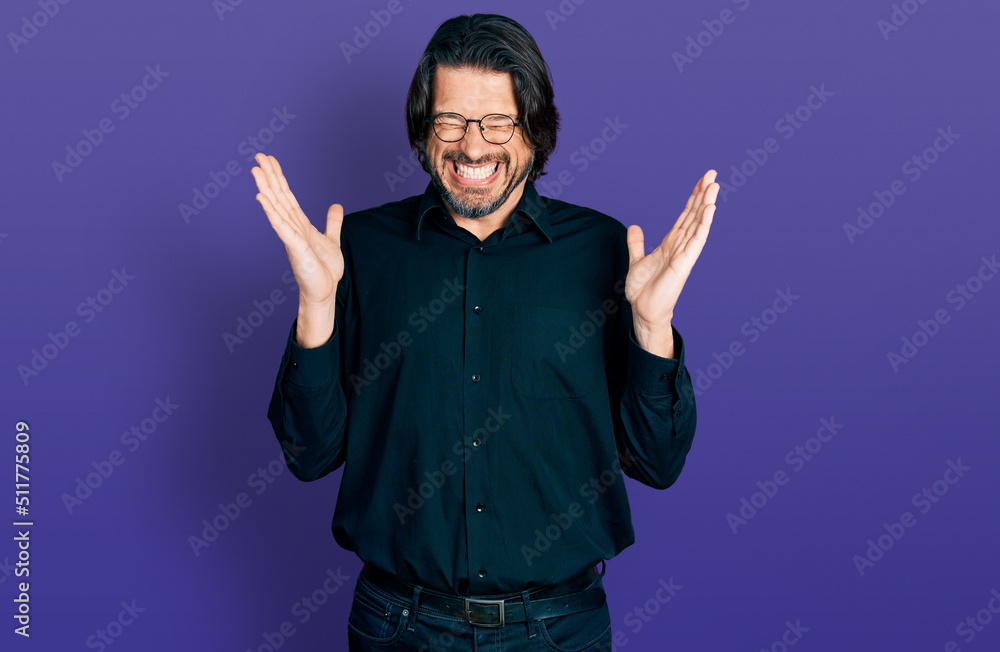 Middle age caucasian man wearing casual clothes and glasses celebrating mad and crazy for success with arms raised and closed eyes screaming excited. winner concept Middle age caucasian man wearing casual clothes and glasses celebrating mad and crazy for success with arms raised and closed eyes screaming excited. winner concept