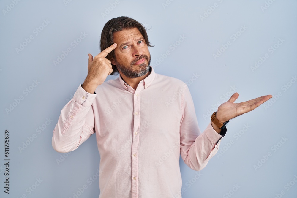 Fototapeta premium Handsome middle age man wearing elegant shirt background confused and annoyed with open palm showing copy space and pointing finger to forehead. think about it.