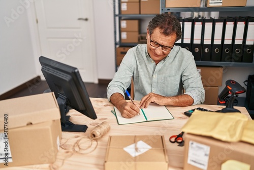 Middle age man ecommerce business worker writing on book at office