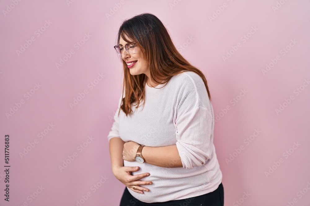 Pregnant woman standing over pink background with hand on stomach because indigestion, painful illness feeling unwell. ache concept. Pregnant woman standing over pink background with hand on stomach because indigestion, painful illness feeling unwell. ache concept.