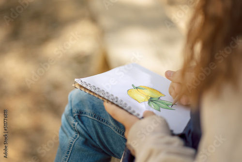 Little girl paints in open air in spring blooming fairytale park. Children's drawings. Creative kid. Joy of childhood. High quality photo