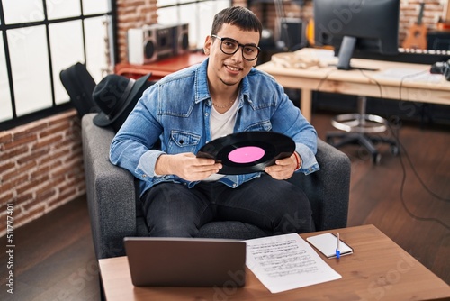 Young man musician hoding vinyl disc at music studio