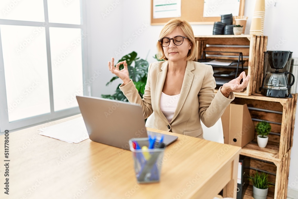 Middle age blonde woman smiling confident doing yoga exercise at office Middle age blonde woman smiling confident doing yoga exercise at office