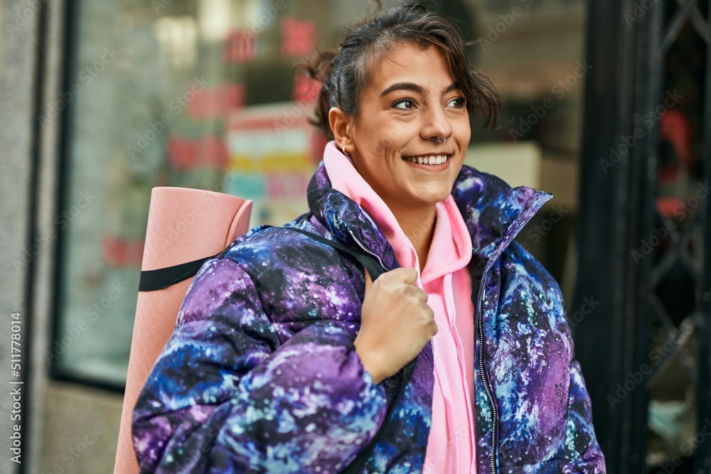 Young hispanic sporty woman smiling happy holding yoga mat at the city. Young hispanic sporty woman smiling happy holding yoga mat at the city.