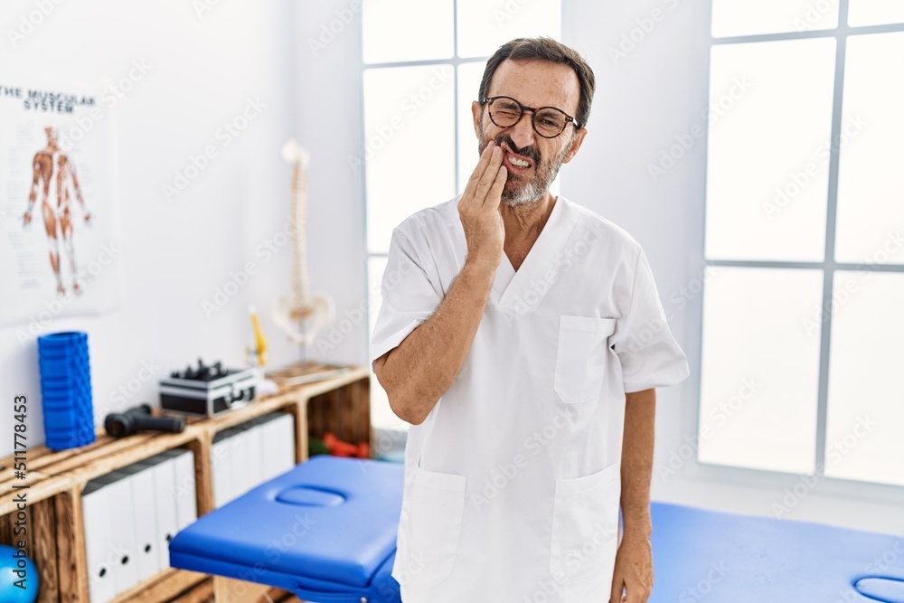 Middle age man with beard working at pain recovery clinic touching mouth with hand with painful expression because of toothache or dental illness on teeth. dentist Middle age man with beard working at pain recovery clinic touching mouth with hand with painful expression because of toothache or dental illness on teeth. dentist