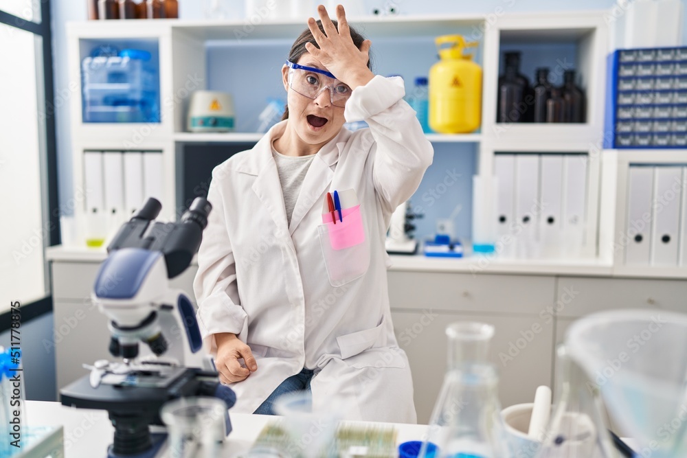 Hispanic girl with down syndrome working at scientist laboratory surprised with hand on head for mistake, remember error. forgot, bad memory concept. Hispanic girl with down syndrome working at scientist laboratory surprised with hand on head for mistake, remember error. forgot, bad memory concept.