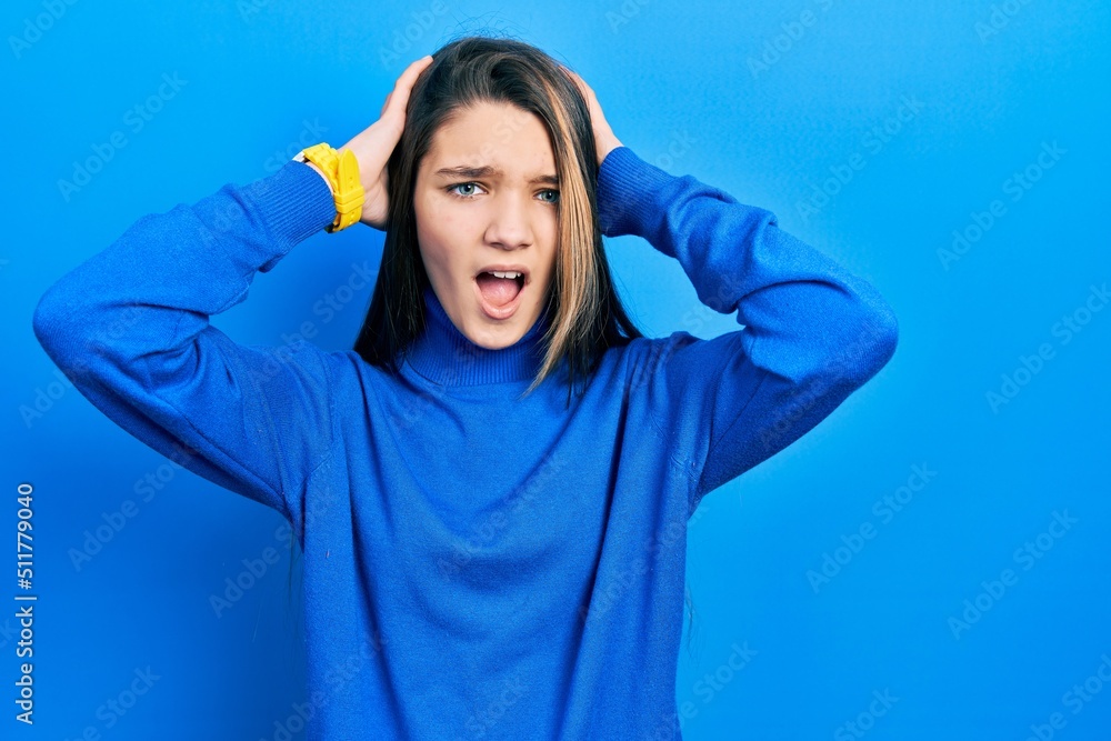 Young brunette girl wearing turtleneck sweater crazy and scared with hands on head, afraid and surprised of shock with open mouth Young brunette girl wearing turtleneck sweater crazy and scared with hands on head, afraid and surprised of shock with open mouth