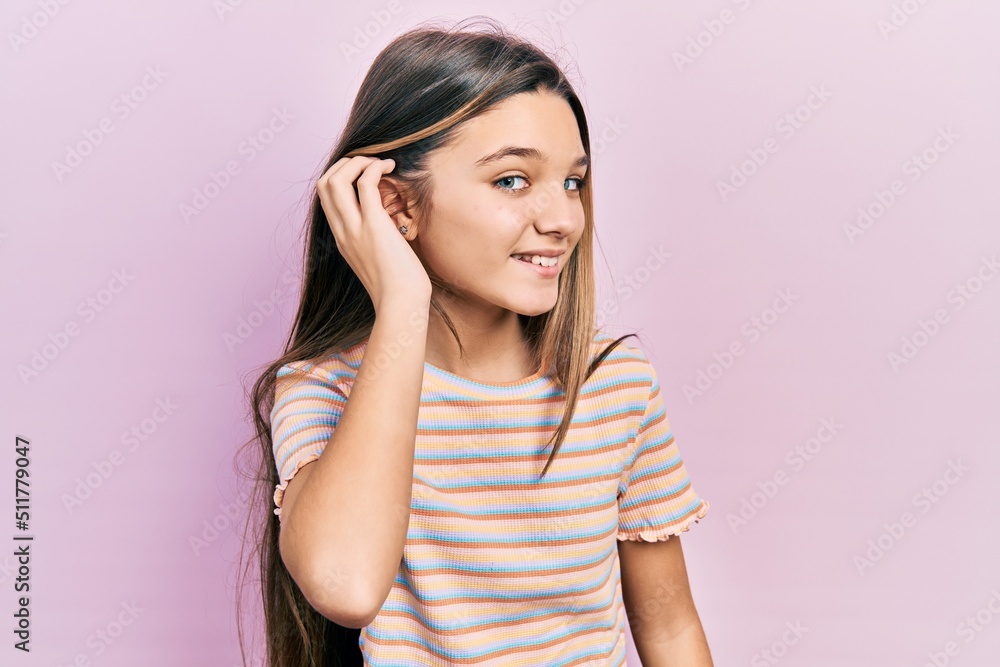 Young brunette girl wearing casual striped t shirt smiling with hand over ear listening and hearing to rumor or gossip. deafness concept. Young brunette girl wearing casual striped t shirt smiling with hand over ear listening and hearing to rumor or gossip. deafness concept.