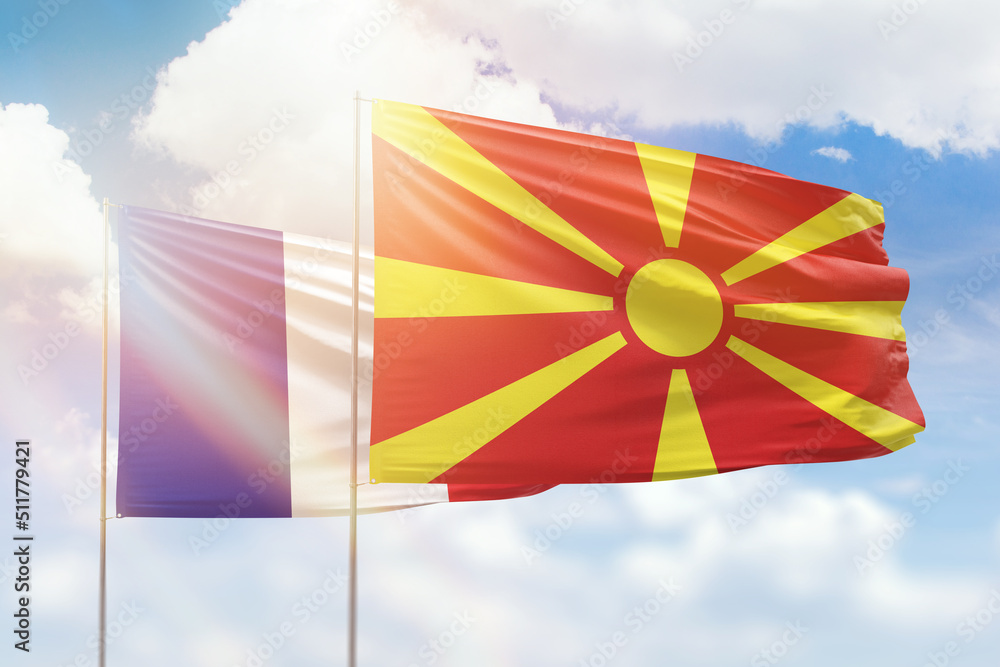 Sunny blue sky and flags of north macedonia and france