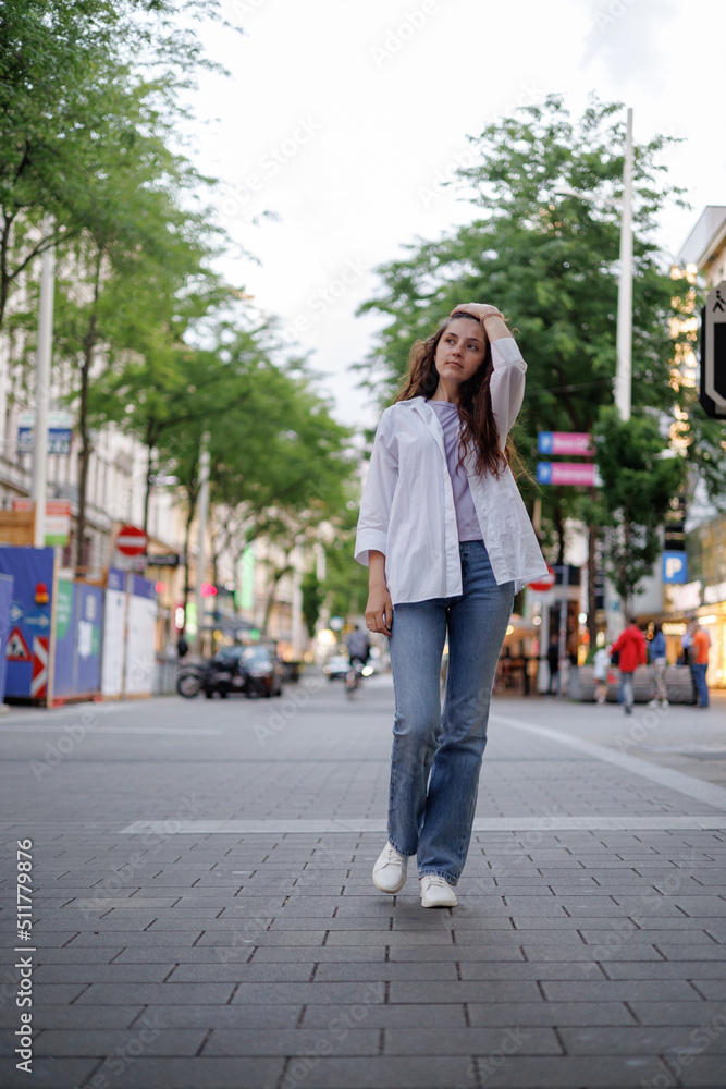 A girl in casual clothes walks in the city center. Beautiful life.
