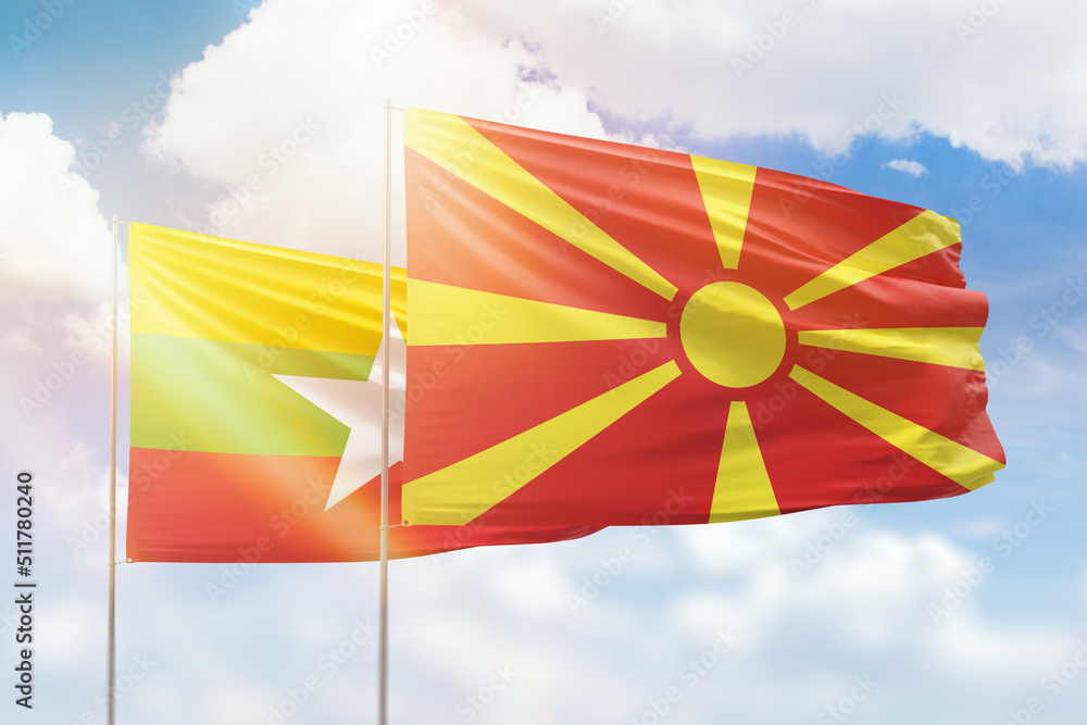 Sunny blue sky and flags of north macedonia and myanmar