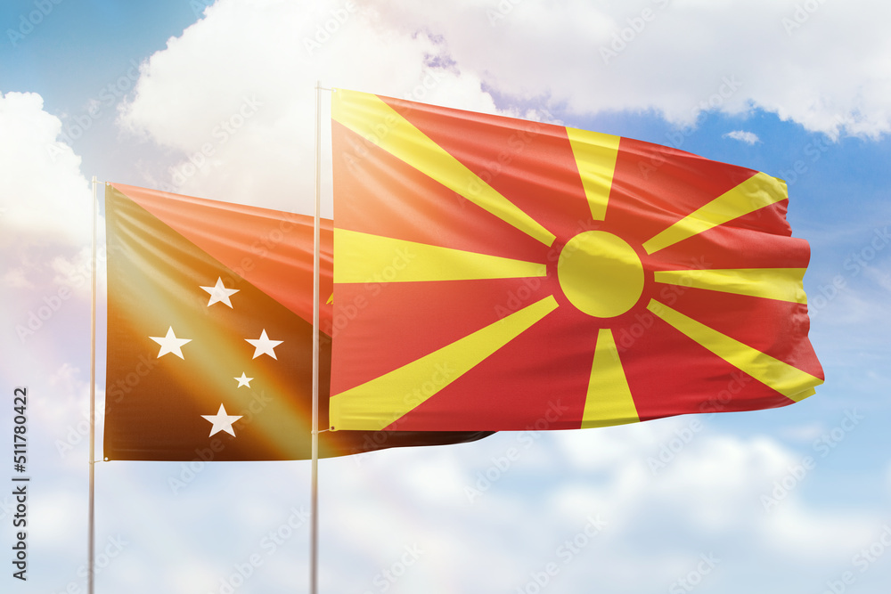 Sunny blue sky and flags of north macedonia and papua new guinea