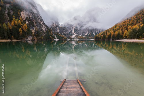 Beautiful autumn day by lake Braies in the Dolomites on a moody morning. Fog and clouds rolling over the mountains. © gljivec