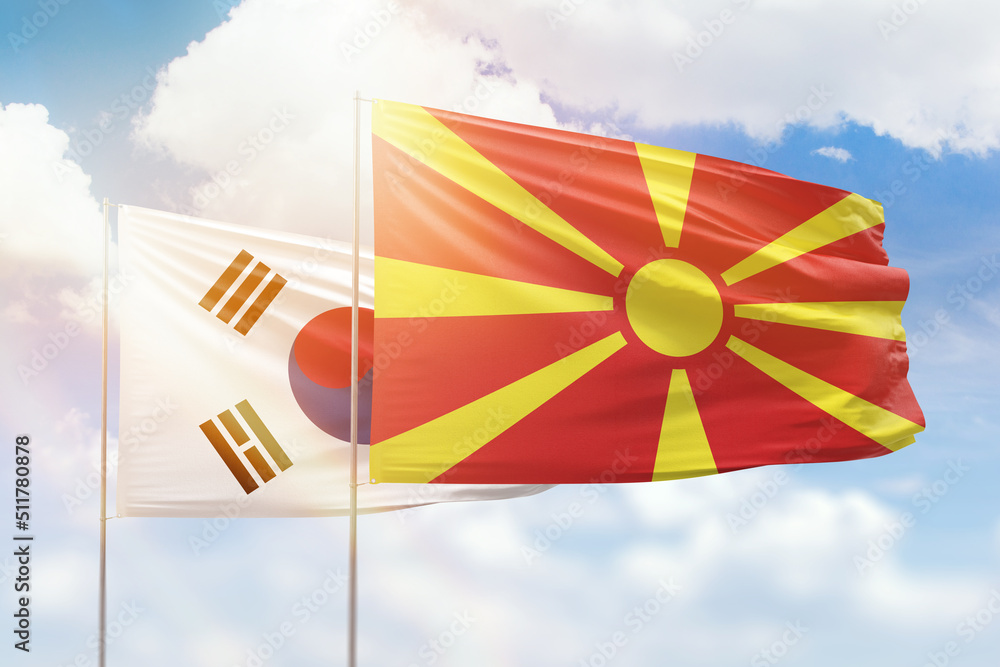 Sunny blue sky and flags of north macedonia and south korea