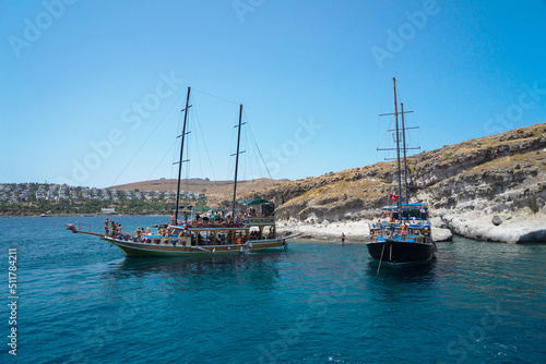 Pleasure yachts for tourists in the Mediterranean or Aegean Sea in Turkey against the backdrop of a city with white houses on a hill, Turkey